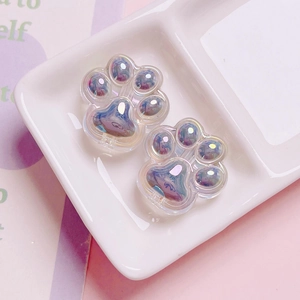 Macro shot of two pearlescent acrylic cat paw beads with iridescent purple and blue sheen