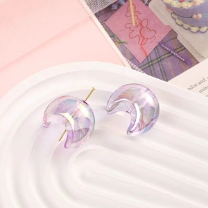 Macro shot of iridescent moon charms with gold pins on a decorative display tray