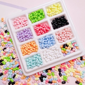 Macro view of colorful acrylic peanut beads in a twelve-grid tray for DIY jewelry making