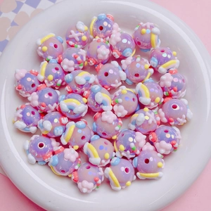 Close-up of hand-painted lavender acrylic beads with cloud and rainbow patterns