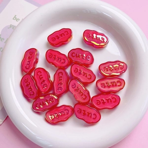 Macro shot of red acrylic 'Cute' beads with gold trim for DIY phone charms and keychains