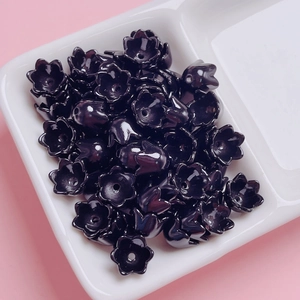 Macro view of glossy black lily of the valley acrylic flower beads in a ceramic tray