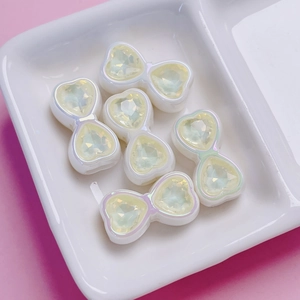 Macro detail of heart bow charms with yellow crystals for DIY jewelry making