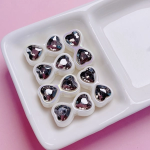 Detail of zircon bow heart beads on a pink background for DIY jewelry making and crafts
