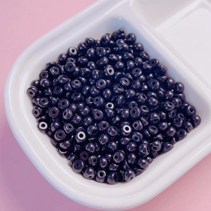 Vue macro de perles en acrylique violet foncé de 4mm dans un plateau pour bijoux fait main