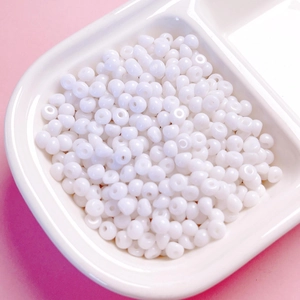 Vue macro de perles en acrylique blanc de 4 mm pour bijoux DIY dans un plateau organiseur