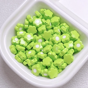 Close-up of green acrylic flower beads with white centers for DIY jewelry making