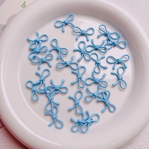 Macro shot of light blue bow-shaped alloy beads for DIY jewelry and phone chain charms