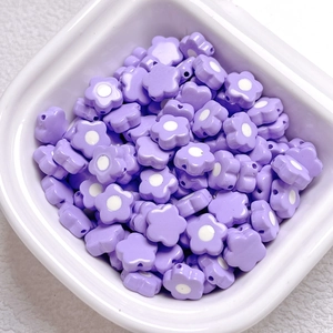 Macro view of light purple acrylic flower beads for DIY crafts in a white ceramic bowl