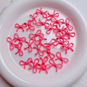 Macro view of bright pink hollow metal bow beads for DIY jewelry and phone chains