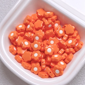 Close-up of orange acrylic flower beads with white centers for DIY jewelry making