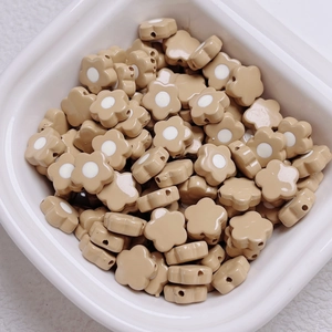 Detail of khaki flower-shaped acrylic beads with white centers for DIY jewelry