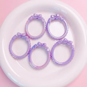 Macro shot of five iridescent lavender rings with bow accents on a white plate
