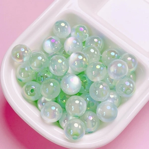 Macro shot of iridescent pale green acrylic cat-eye round beads in storage tray