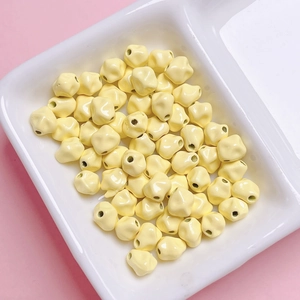 Detalle de cuentas de estrella en esmalte amarillo de 7mm para joyería DIY en un plato blanco