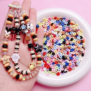 Handmade beaded phone strap with cute cat charm and colorful donut beads on pink background