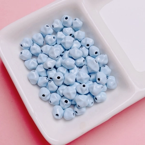 Primer plano de cuentas de carambola de aleación azul claro de 7mm en un plato blanco