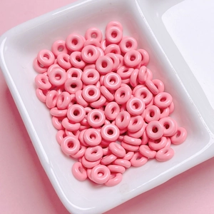 Close-up of pink doughnut-shaped alloy beads for DIY jewelry and phone chain making