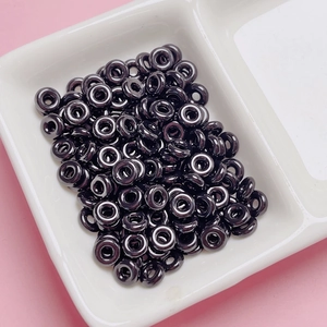 Close-up of glossy black donut beads for DIY jewelry making in a ceramic dish