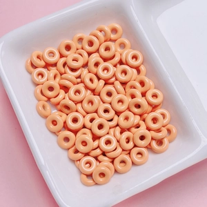 Macro detail of glossy orange donut-shaped alloy beads for DIY jewelry making