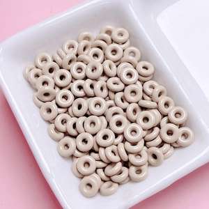 Macro shot of glossy beige donut beads stacked in a white tray for DIY crafts