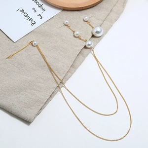 Asymmetrische lange parelkwast oorbellen in goud op een minimalistische linnen achtergrond