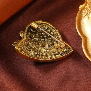 Macro view of vintage gold heart brooch showing hammered texture and secure pin clasp
