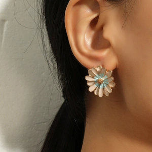 Detail of daisy stud earrings with pink and blue enamel petals and golden center
