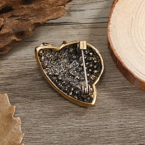Detailed back view of vintage bronze heart brooch with safety pin on rustic wood background