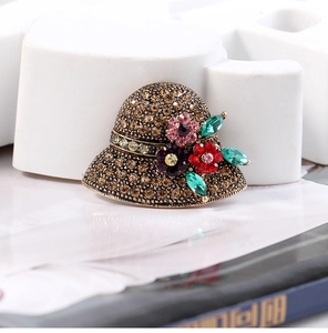 Close-up of vintage hat brooch with colorful crystals and bronze metal base detail