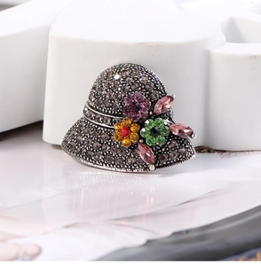 Macro detail of vintage sun hat brooch with colorful crystals and grey rhinestones