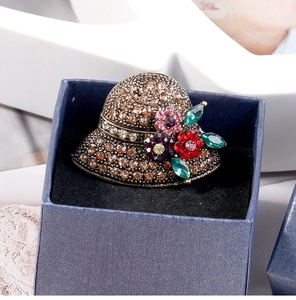 Close-up of vintage bronze hat brooch with colorful crystals in a blue jewelry box