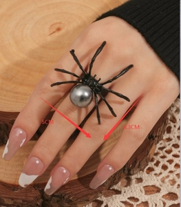 Primer plano de anillo de araña negro con perla gris, medidas exactas de 5cm por 4,3cm
