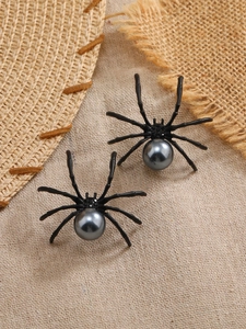 Primer plano de pendientes de araña gótica con perlas oscuras sobre fondo de lino