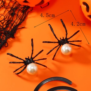 Elegantes pendientes de araña negra con perla blanca sobre fondo naranja festivo