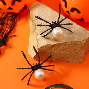 Pendientes de araña negra elegantes con gran perla blanca sobre fondo de Halloween