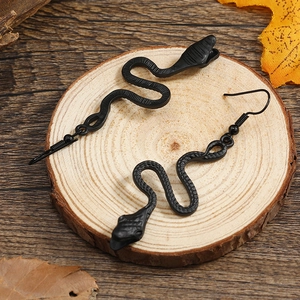 Detailed macro view of matte black snake earrings with realistic scale texture on wood