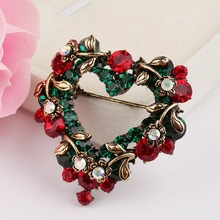 Detailed close-up of heart-shaped Christmas brooch with red and green crystals