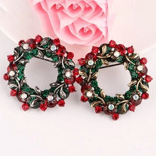 Close-up of elegant Christmas wreath brooch with red and green rhinestones and floral details