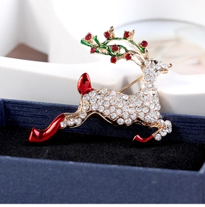 Détail macro de broche renne avec cristaux blancs et émail rouge sur écrin de bijoux