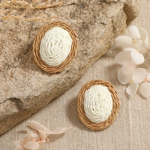 Close-up detail of woven oval earrings featuring natural fiber textures and bohemian style