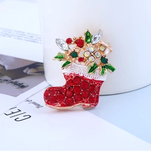 Détail d'une broche botte de Noël dorée avec strass rouges et feuilles en émail vert
