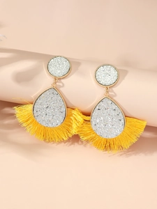 Macro view of bohemian gold alloy earrings with sparkling crystals and yellow silk tassels