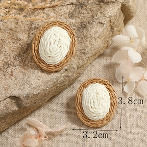Detail view of woven oval earrings with brown and beige straw texture and 3.8cm size