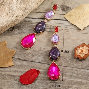 Orecchini vintage in oro con strass viola e rossi su uno sfondo in legno rustico