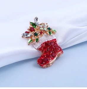 Détail d'une broche chaussette de Noël dorée ornée de strass rouges et cristaux verts
