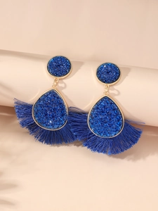 Detail of bohemian fan-shaped drop earrings with dark blue tassels and crystal inlay