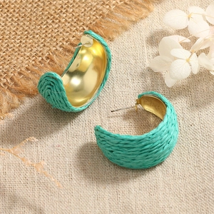 Detailed close-up of blue woven raffia on golden C-shaped hoop earrings