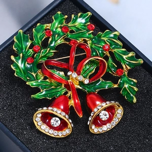 Macro shot of Christmas bell brooch with green enamel leaves and red crystals