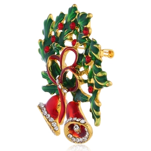 Detail view of alloy Christmas bell brooch with holly leaves and red enamel finish